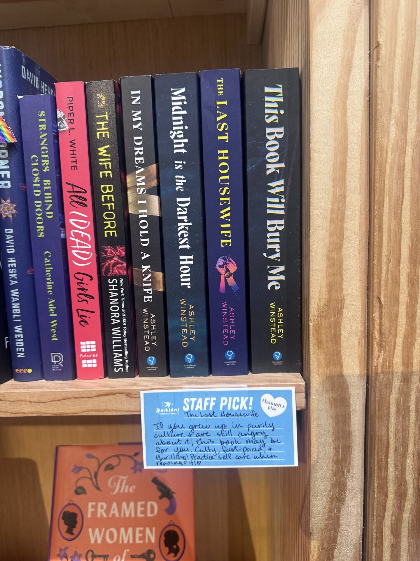A shelf of dark thriller spines, most of them Ashley Winstead, with a blue handwritten STAFF PICK card below carrying the Blackbird Books & Coffee logo and Hannah's recommendation of The Last Housewife.